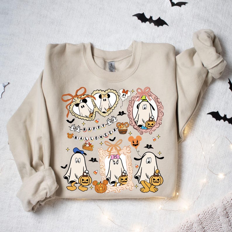 Puede incluir: Sudadera beige con un dise&ntilde;o de Halloween. El dise&ntilde;o presenta fantasmas de dibujos animados, calabazas y el texto "HAPPY HALLOWEEN". Los fantasmas est&aacute;n en marcos y sostienen calabazas. Mickey Mouse y Minnie Mouse tambi&eacute;n aparecen en el dise&ntilde;o.