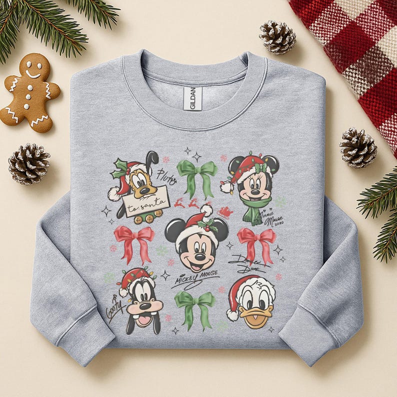 May include: A light gray sweatshirt featuring Disney characters in Christmas attire. Mickey Mouse, Pluto, Goofy, and Donald Duck are depicted with Santa hats and bows. The sweatshirt has a crew neck and long sleeves.