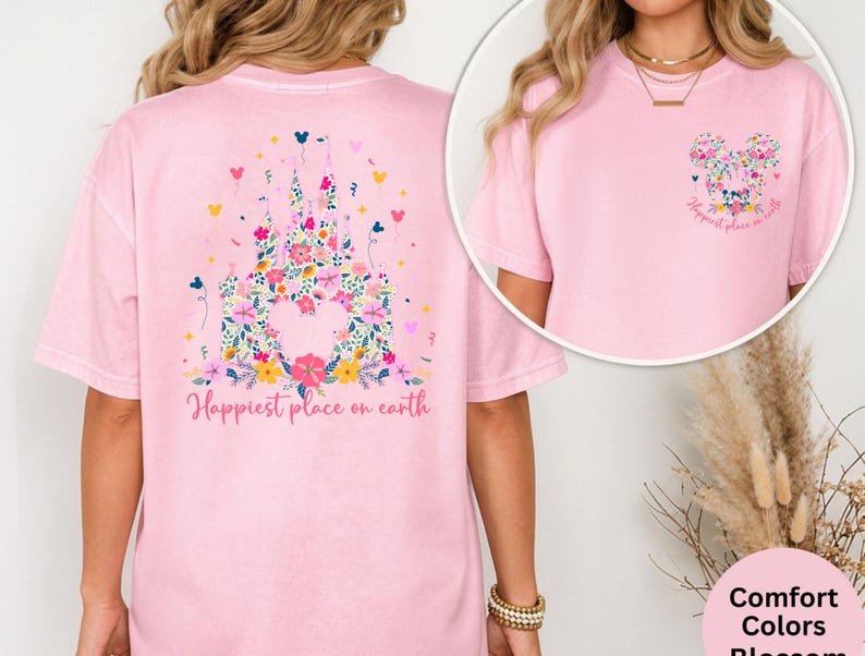 May include: A light pink t-shirt featuring a floral castle design on the back and a floral Mickey Mouse head on the front. The text "Happiest place on earth" is printed on the front and back of the shirt. The shirt is made of a soft, comfortable material.