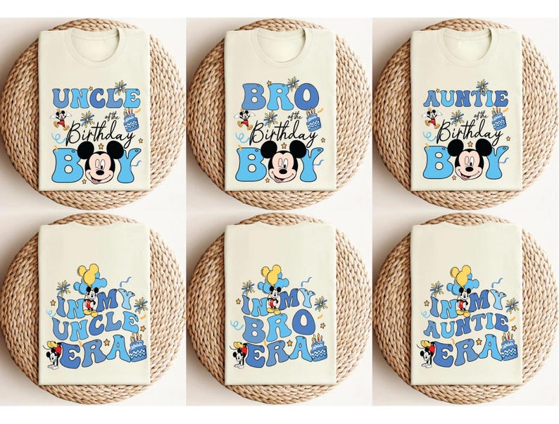 Op de afbeelding: Cr&egrave;mekleurige T-shirts met blauwe tekst en Mickey Mouse-afbeeldingen. De shirts tonen zinnen als "Uncle Birthday Boy", "Bro Birthday Boy" en "In My Uncle Era". Elk gevouwen T-shirt ligt op een geweven mat.