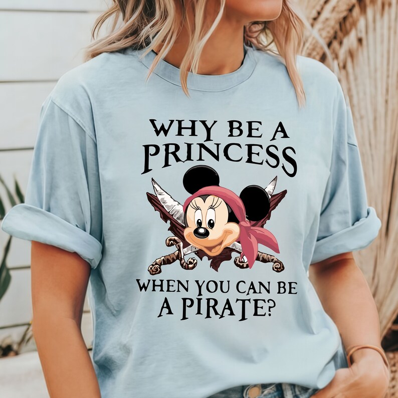 May include: Light blue t-shirt with a graphic of Mickey Mouse dressed as a pirate with the text "Why be a princess when you can be a pirate?"