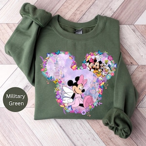 May include: A green sweatshirt with a floral Mickey Mouse design. The design features Mickey Mouse and Minnie Mouse with a pink castle in the background.