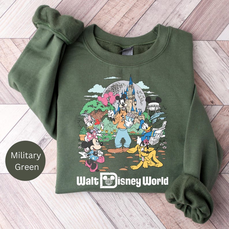 May include: A green sweatshirt with a graphic print of Mickey Mouse and friends at Walt Disney World. The sweatshirt has a crew neck and long sleeves.