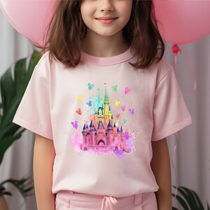 May include: A pink t-shirt with a watercolor illustration of a pink castle with rainbow accents and Mickey Mouse balloons.