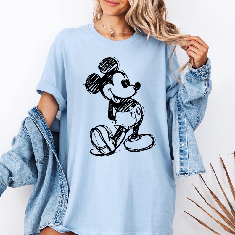 May include: A light blue t-shirt with a black and white sketch of Mickey Mouse on the front.