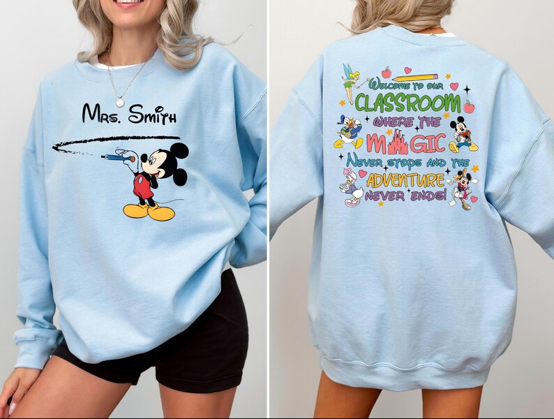 May include: Light blue sweatshirt with a Mickey Mouse design on the front and a Disney-themed quote on the back. The quote reads "Welcome to our classroom where the magic never stops and the adventure never ends".