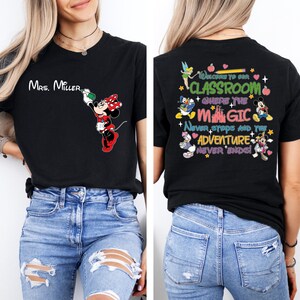 May include: Black t-shirt with a Mickey Mouse design on the front and a Disney-themed classroom quote on the back. The quote reads "Welcome to our classroom where the magic never stops and the adventure never ends!"