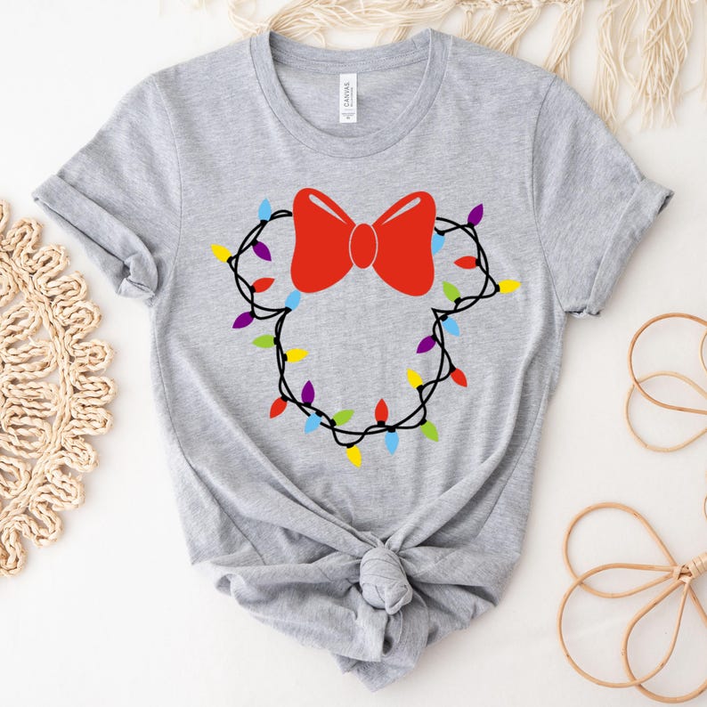 May include: A gray t-shirt with a red bow and a string of colorful lights in the shape of a mouse head.