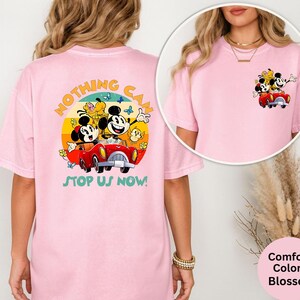 Pode incluir: T-shirt rosa claro com um desenho do Mickey e da Minnie Mouse num carro vermelho, com o texto "Nothing Can Stop Us Now!" nas costas. Uma vers&atilde;o mais pequena do desenho est&aacute; na frente. A t-shirt &eacute; um Comfort Colors Blossom.