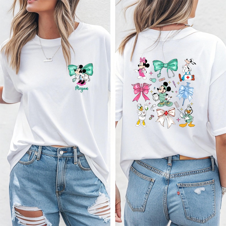May include: White t-shirt featuring a Minnie Mouse and Mickey Mouse design with a teal bow. The shirt has the name "Megan" printed below the design. The back of the shirt has multiple cartoon character designs.