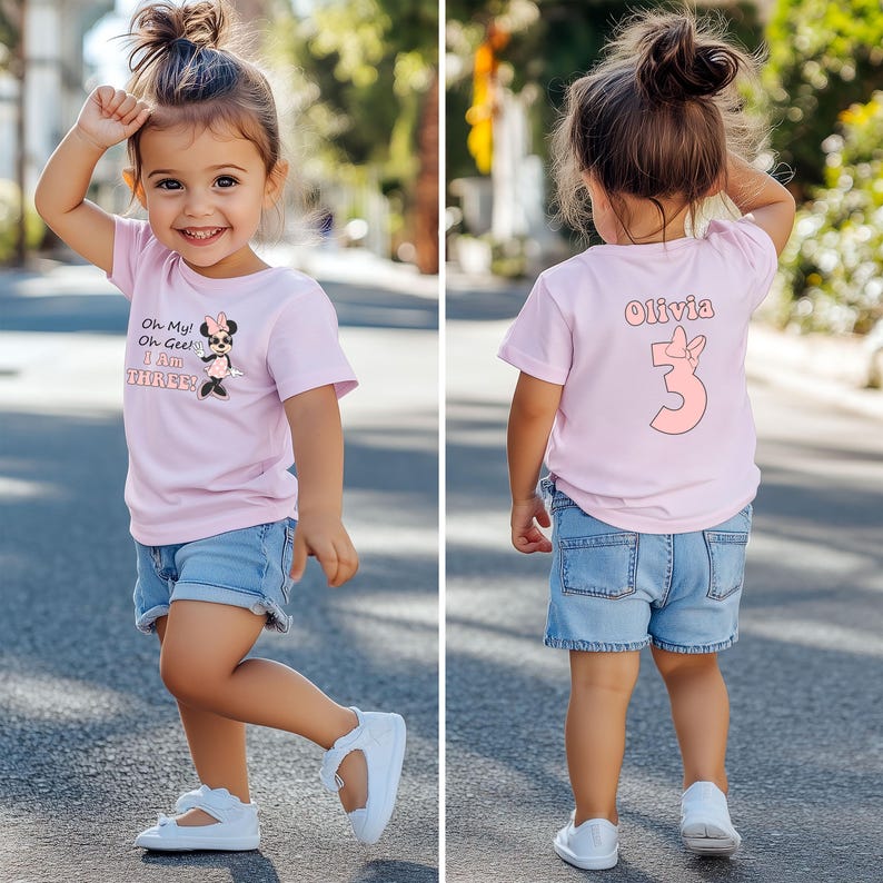 May include: A young child wearing a light pink t-shirt and denim shorts. The front of the shirt has the text "Oh My! Oh Gee! I Am THREE!" with a Minnie Mouse graphic. The back of the shirt has the name "Olivia" and the number "3".