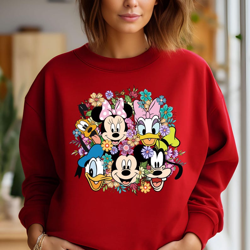 May include: Red sweatshirt with a colorful graphic print of Mickey Mouse, Minnie Mouse, Donald Duck, Goofy, and Pluto surrounded by flowers.