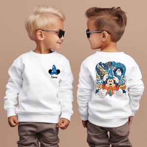May include: Two white sweatshirts with a Mickey Mouse design. One sweatshirt has a small Mickey Mouse wearing a sorcerer's hat on the front, the other has a larger Mickey Mouse wearing a sorcerer's hat on the back. Both sweatshirts have the text "Name" on the front.