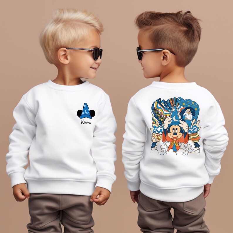 May include: Two white sweatshirts with a Mickey Mouse design. One sweatshirt has a small Mickey Mouse wearing a sorcerer's hat on the front, the other has a larger Mickey Mouse wearing a sorcerer's hat on the back. Both sweatshirts have the text "Name" on the front.