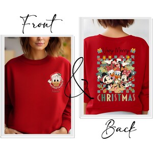May include: Red Christmas sweatshirt featuring Donald Duck in a Santa hat on the front. The back of the sweatshirt displays a festive design with Mickey and Minnie Mouse, Donald Duck, and Goofy, with the words "Very Merry Christmas".