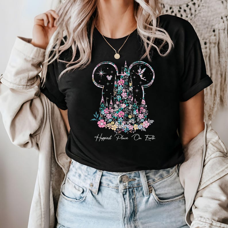 May include: Black t-shirt with a floral design of Cinderella's castle inside Mickey Mouse ears. The text "Happiest Place On Earth" is printed below the design.