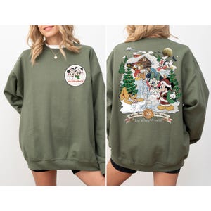May include: A green sweatshirt with a Christmas scene featuring Mickey Mouse and friends on the back. The front of the sweatshirt has a small image of Mickey Mouse and Minnie Mouse with the text "Walt Disney World".