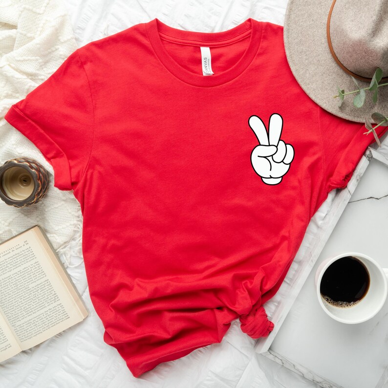 May include: Red short-sleeved t-shirt with a white peace sign graphic.