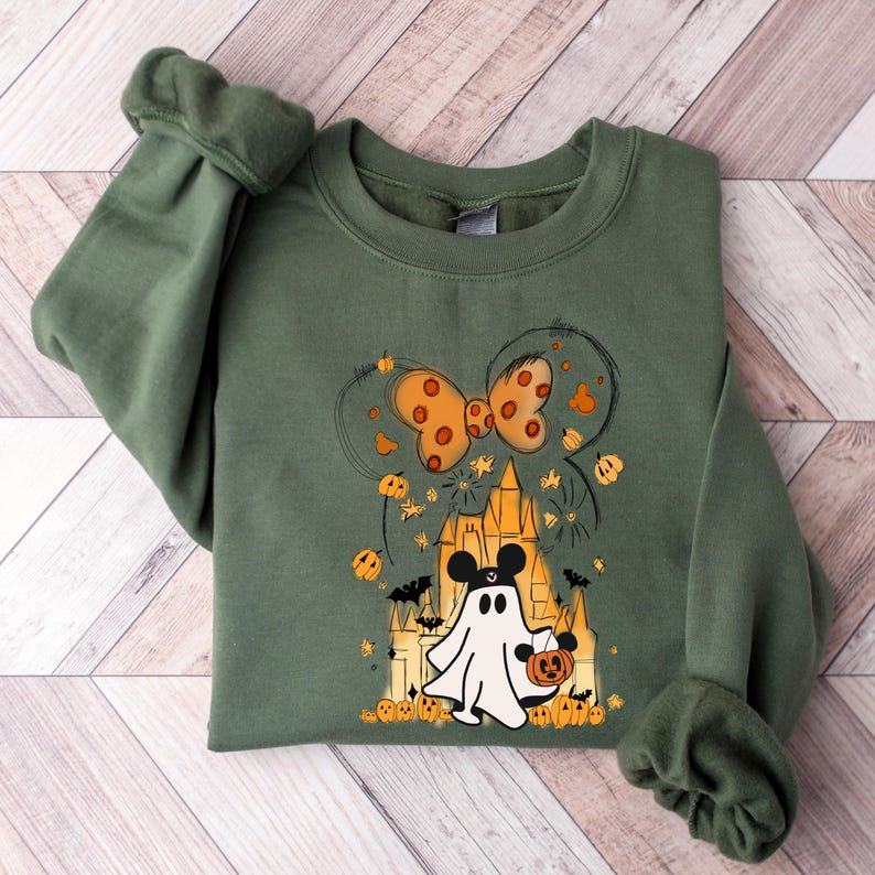 May include: A green sweatshirt with a Halloween-themed design featuring a ghost Mickey Mouse holding a pumpkin, a castle, and a bow with orange polka dots.