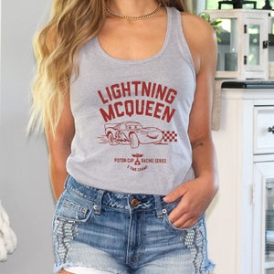 May include: Gray tank top with a red graphic of Lightning McQueen from the Disney Pixar movie Cars. The graphic includes the text "Lightning McQueen", "Piston Cup", and "Racing Series".