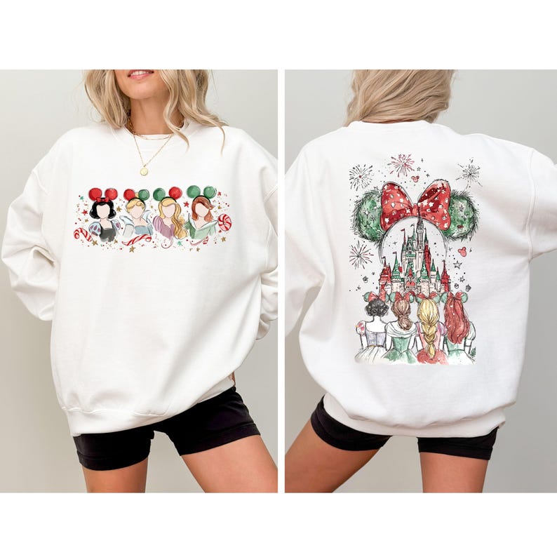 May include: White sweatshirt featuring a watercolor design of Disney princesses with holiday-themed Mickey Mouse ears on the front. The back of the sweatshirt showcases a castle and more princesses with fireworks.