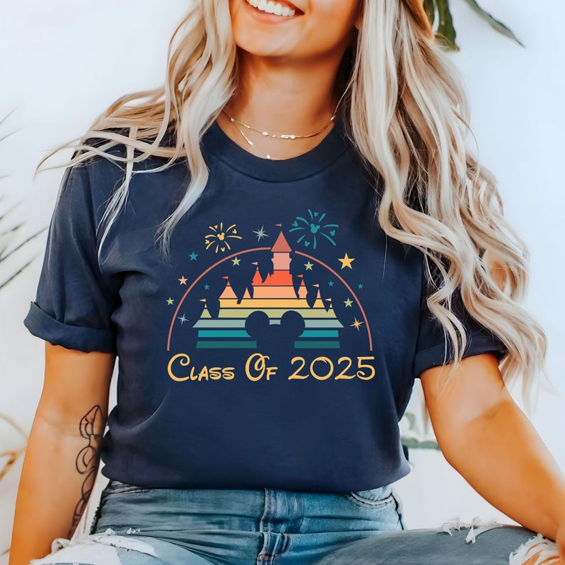 May include: A navy blue t-shirt with a rainbow-colored silhouette of a castle and fireworks. The text "Class of 2025" is printed below the castle.