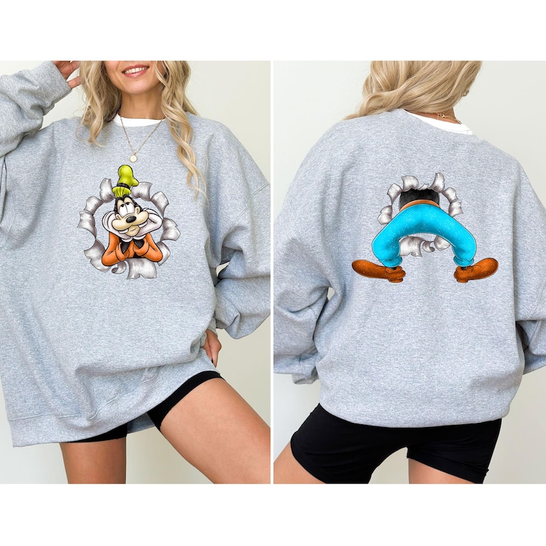 K&ouml;nnte beinhalten: Ein hellgraues Sweatshirt mit einem Cartoon-Charakter-Design. Die Vorderseite des Sweatshirts zeigt das Gesicht der Figur, das aus einem zerrissenen Loch herausragt. Die R&uuml;ckseite des Sweatshirts zeigt die Beine und F&uuml;&szlig;e der Figur.