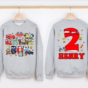 May include: Gray sweatshirt with a Cars birthday boy design on the front and a red number 2 with the name Henry on the back.
