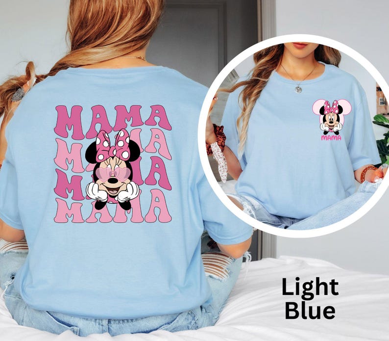 Puede incluir: Camiseta azul claro con un dise&ntilde;o de Minnie Mouse con gafas de sol y la palabra "MAMA" en rosa. La parte trasera de la camiseta tiene un gr&aacute;fico m&aacute;s grande de Minnie Mouse y la palabra "MAMA" repetida.