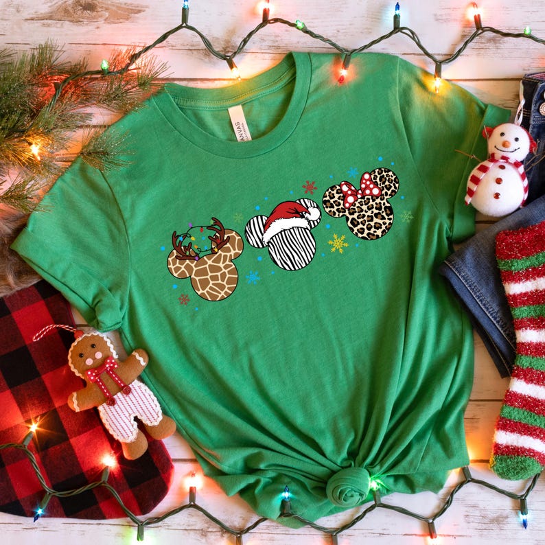 May include: Green t-shirt with a Christmas-themed design featuring three Mickey Mouse ears with different animal print patterns and holiday decorations.