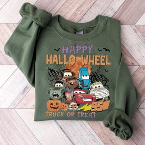 May include: Green sweatshirt with a graphic of Cars characters dressed up for Halloween. The text reads "Happy Hallo-Wheel Truck or Treat" with a lightning bolt and the number 95.