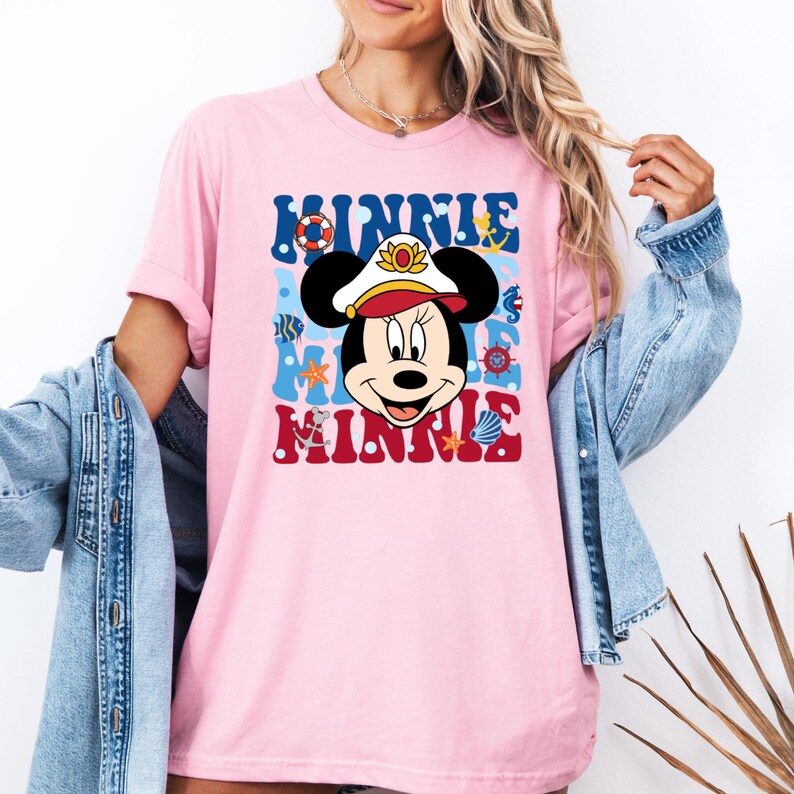 May include: Pink t-shirt with a cartoon image of Minnie Mouse wearing a captain's hat and surrounded by nautical themed graphics. The text "Minnie Mouse" is printed in a retro font.