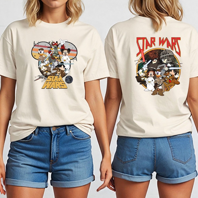 May include: Cream-colored t-shirt featuring a Star Wars graphic with Disney characters on the front and back. The front design includes Mickey Mouse, Donald Duck, and other characters in a circular design. The back features the Star Wars logo.