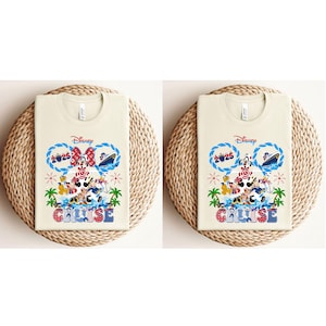 May include: Two cream-colored t-shirts with a Disney Cruise design. The design features Mickey and Minnie Mouse, a cruise ship, and the text "Cruise 2025". The shirts are displayed on a woven, circular placemat.