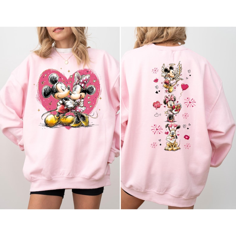 May include: A light pink sweatshirt featuring Mickey and Minnie Mouse embracing within a pink heart. The back of the sweatshirt displays Mickey, Minnie, and Pluto with hearts and other graphics. The sweatshirt is a casual, long-sleeved garment.
