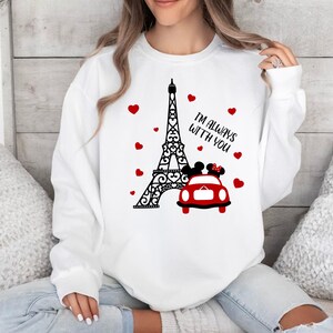 May include: White sweatshirt with a black and white graphic of the Eiffel Tower, a red car, and two cartoon figures. The text "I'm always with you" is printed on the sweatshirt.