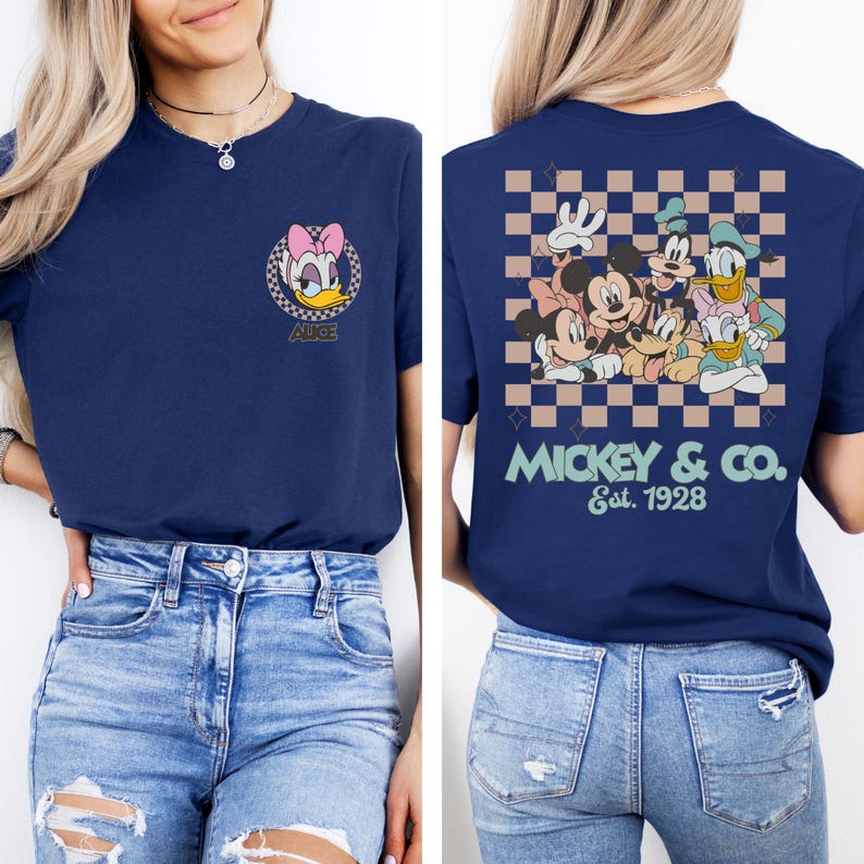 May include: A navy blue t-shirt with a checkered pattern on the back. The back of the shirt features a group of Disney characters including Mickey Mouse, Minnie Mouse, Donald Duck, Goofy, and Pluto. The text "MICKEY & CO. Est. 1928" is printed below the characters. The front of the shirt features a cartoon image of Daisy Duck with the text "ALICE" below.