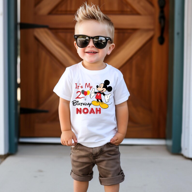 May include: White t-shirt with a red Mickey Mouse character holding balloons. The text on the shirt reads "It's My 2nd Birthday NOAH".