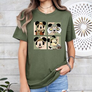 K&ouml;nnte beinhalten: Olivgr&uuml;nes T-Shirt mit einem Vier-Panel-Design von Mickey Mouse in Safari-Kleidung. Jedes Panel zeigt Mickey mit Safarihut und Outfit, mit Fernglas. Das Shirt ist ein l&auml;ssiger Stil mit kurzen &Auml;rmeln.