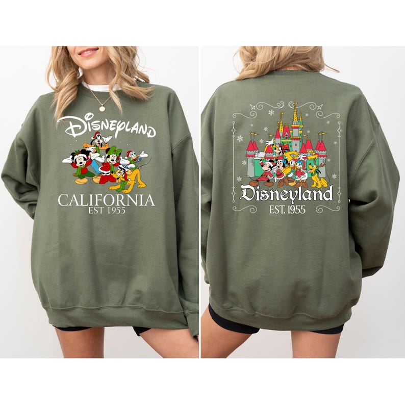 May include: Olive green Disneyland sweatshirt with front and back graphics. The front features the Disneyland logo, cartoon characters, and "CALIFORNIA EST 1955." The back displays the Disneyland castle, characters, and logo. A cozy, long-sleeved top.