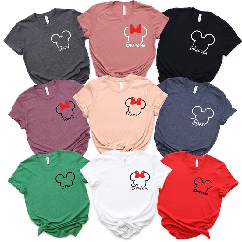 Puede incluir: Nueve camisetas diferentes con un dise&ntilde;o de cabeza de Mickey Mouse y varios t&iacute;tulos de miembros de la familia. Las camisetas son de diferentes colores, incluyendo rojo, verde, azul, blanco, rosa y negro.
