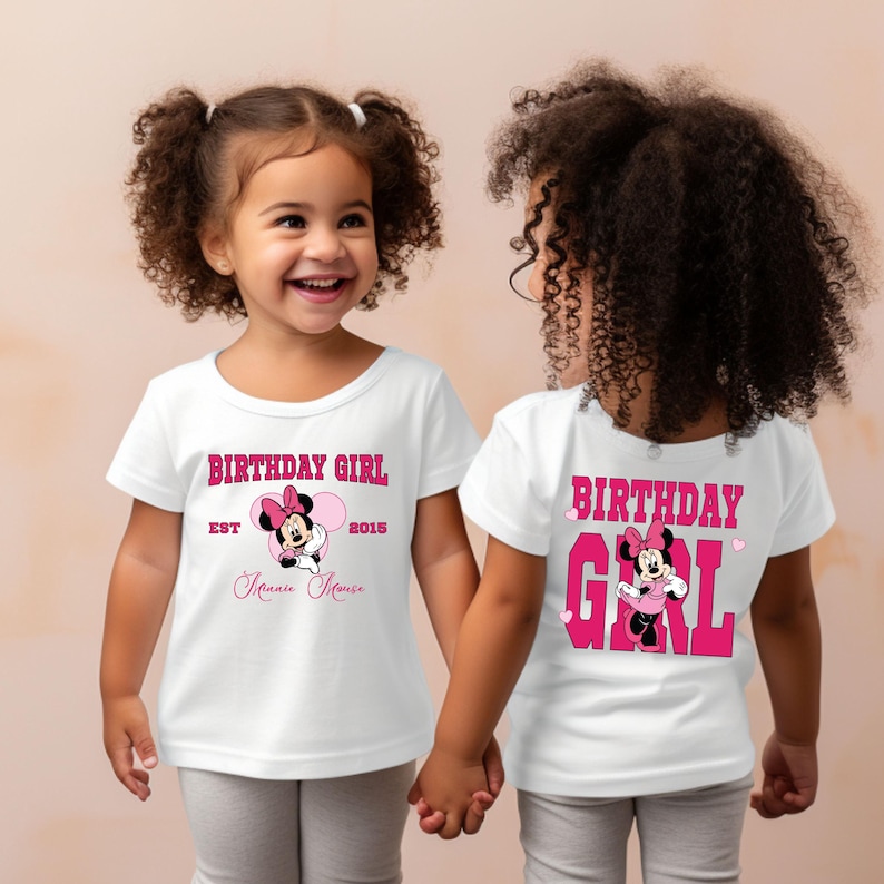以下が含まれることがあります： ピンクと黒のミニーマウスのグラフィックが描かれた白いTシャツ2枚。1枚は「Birthday Girl Est 2015 Minnie Mouse」と書いてあり、もう1枚はハートマーク付きで「Birthday Girl」と書いてあります。