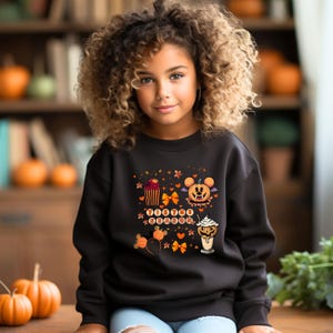 Puede incluir: Una sudadera negra con un dise&ntilde;o de Halloween. El gr&aacute;fico incluye una calabaza de Mickey Mouse, cupcakes, lazos y el texto "Boo-tiful Season". El dise&ntilde;o es en colores naranja, marr&oacute;n y blanco. La sudadera la lleva una persona joven.