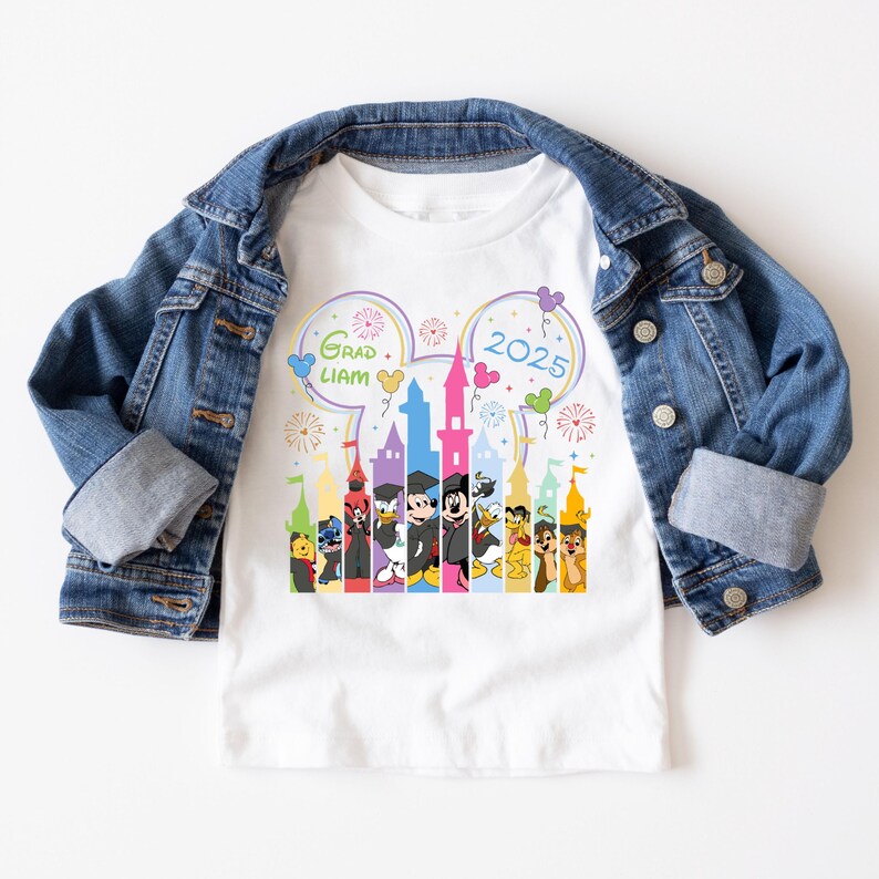 Puede incluir: Camiseta blanca con una ilustraci&oacute;n colorida de un castillo de Disney con Mickey Mouse y otros personajes. El texto "Grad Liam 2025" est&aacute; impreso en la camiseta.