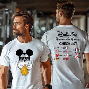 Puede incluir: Camiseta blanca con una imagen de dibujos animados de Mickey Mouse con gafas de sol y sosteniendo una jarra de cerveza. La parte posterior de la camiseta tiene una lista de verificaci&oacute;n con banderas de diferentes pa&iacute;ses y el texto "Drinking Around the World Checklist".