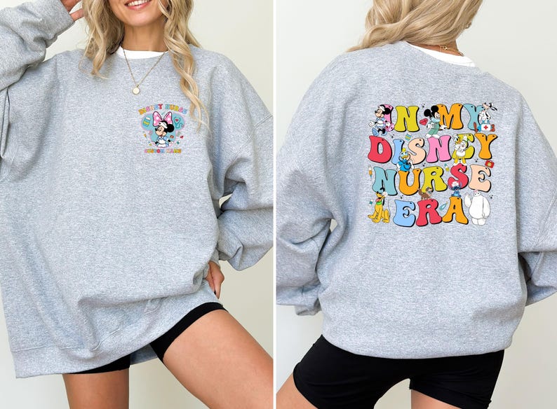 May include: A light gray sweatshirt with a colorful graphic on the front and back. The front features Minnie Mouse with text, and the back displays the words "In My Disney Nurse Era" with Disney characters. The sweatshirt is a casual style.
