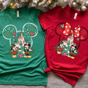 Puede incluir: Dos camisetas, una verde y otra roja, con un dise&ntilde;o de Mickey Mouse con tem&aacute;tica navide&ntilde;a. La camiseta verde presenta a Mickey Mouse y Minnie Mouse de pie frente al Castillo de Cenicienta con un &aacute;rbol de Navidad. La camiseta roja presenta a Mickey Mouse y Minnie Mouse de pie frente al Castillo de Cenicienta con un lazo rojo.