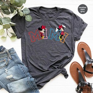 May include: A heather dark grey t-shirt with a colorful "MIMI" graphic featuring two cartoon Minnie Mouse characters.
