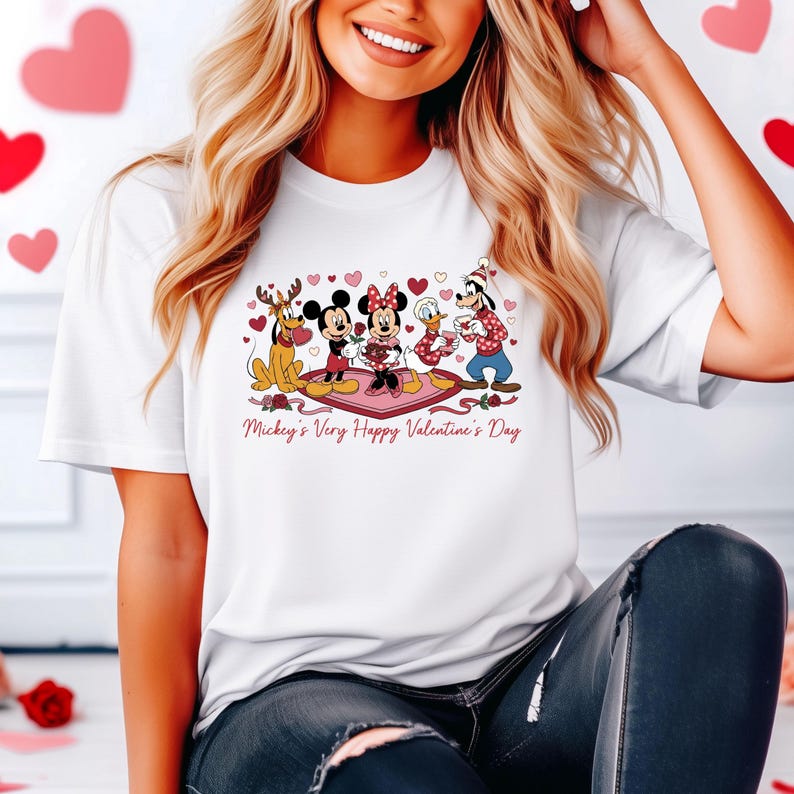 May include: White t-shirt featuring a Valentine's Day graphic with Mickey Mouse, Minnie Mouse, Donald Duck, Goofy, and Pluto. The graphic includes hearts and the text "Mickey's Very Happy Valentine's Day".