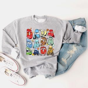 May include: Gray sweatshirt with a graphic of cartoon cars spelling out "DADA" in colorful letters.